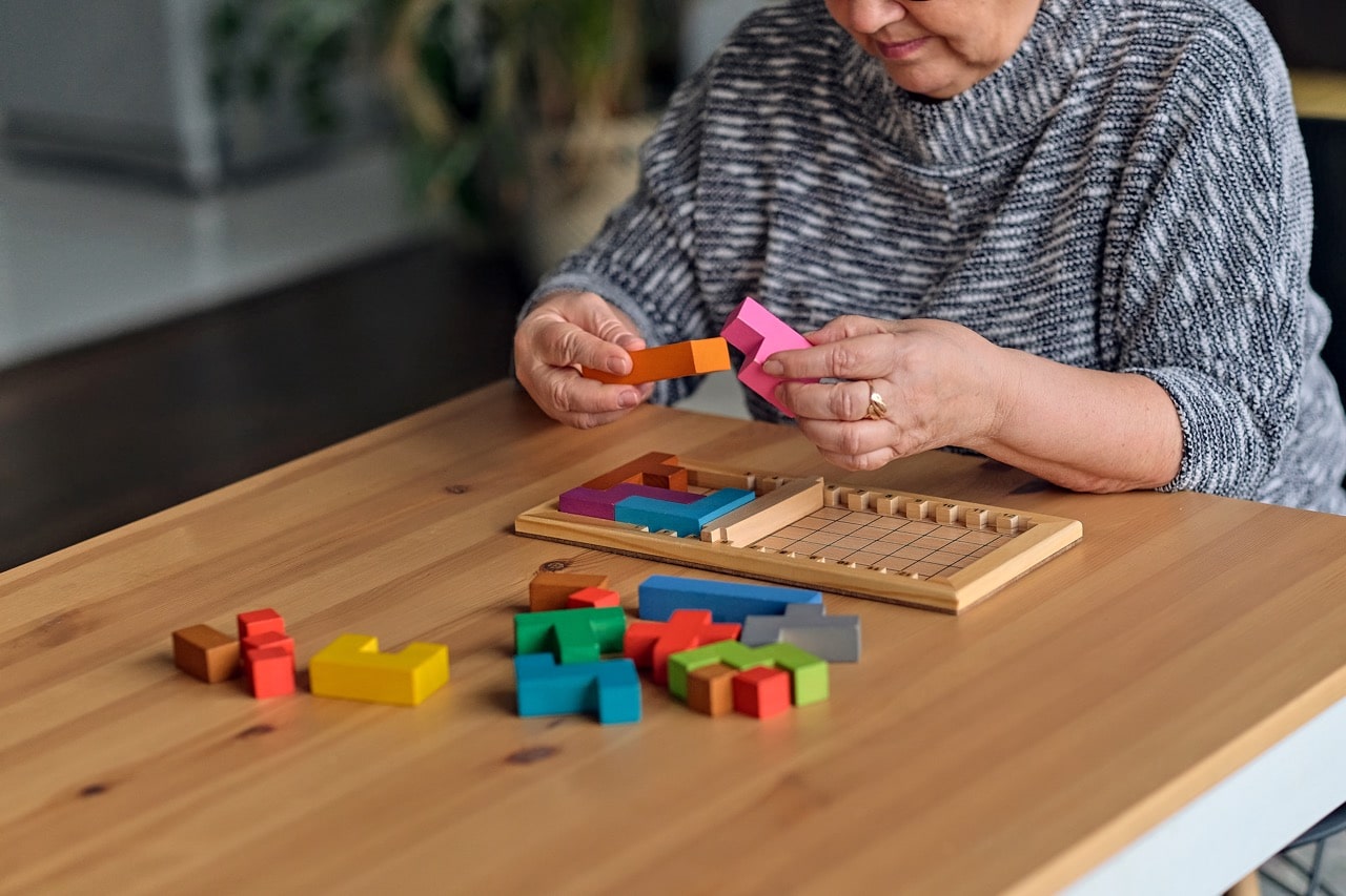 An elderly woman sorting out a jigsaw puzzle