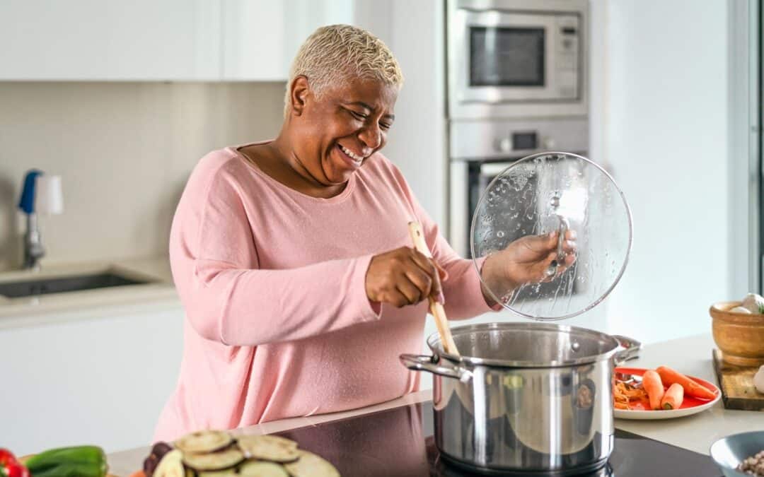 An elderly woman happily cooking a healthy meal
