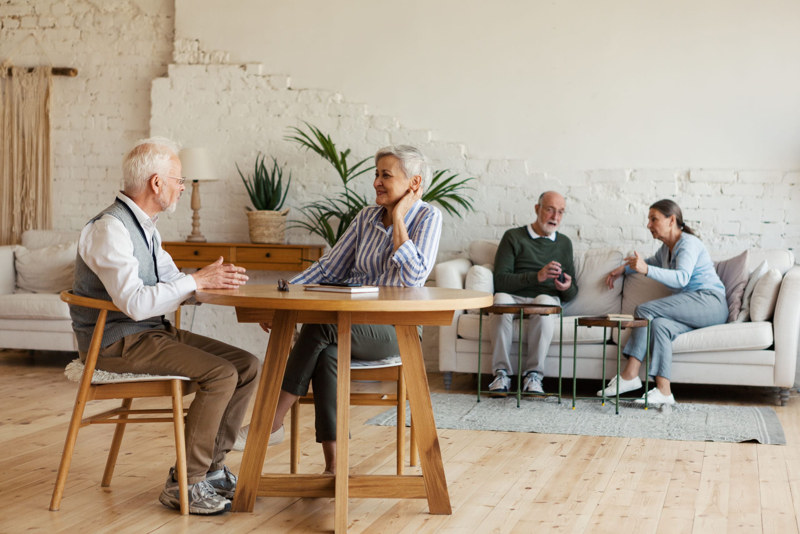 Seniors gathered together in the common room of an Assisted Living Facility.